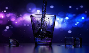 Water being poured into a glass against a sparkly blue and violet background